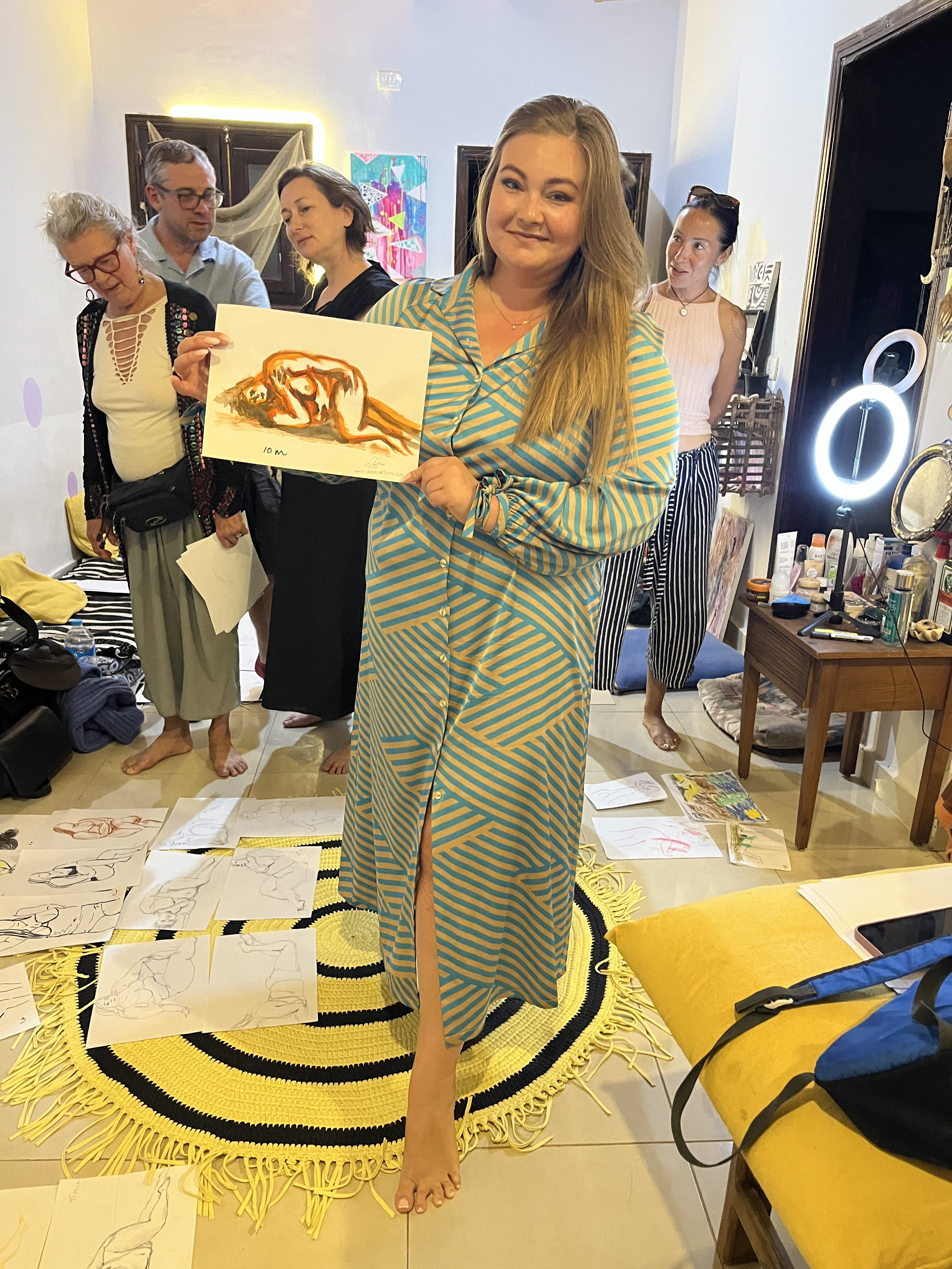 Woman proudly holding a life drawing created during an art class.