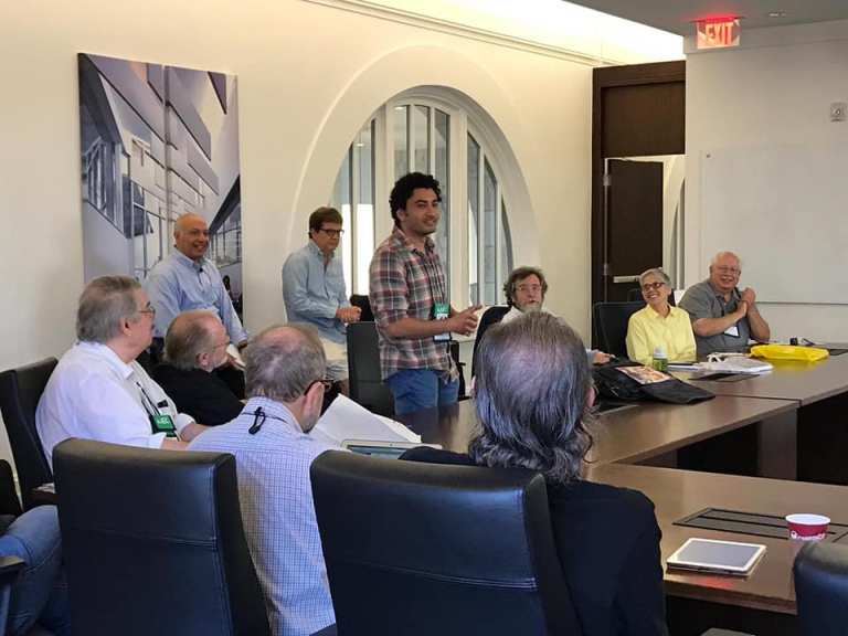 A man stands speaking to a group in a conference room during a business meeting.