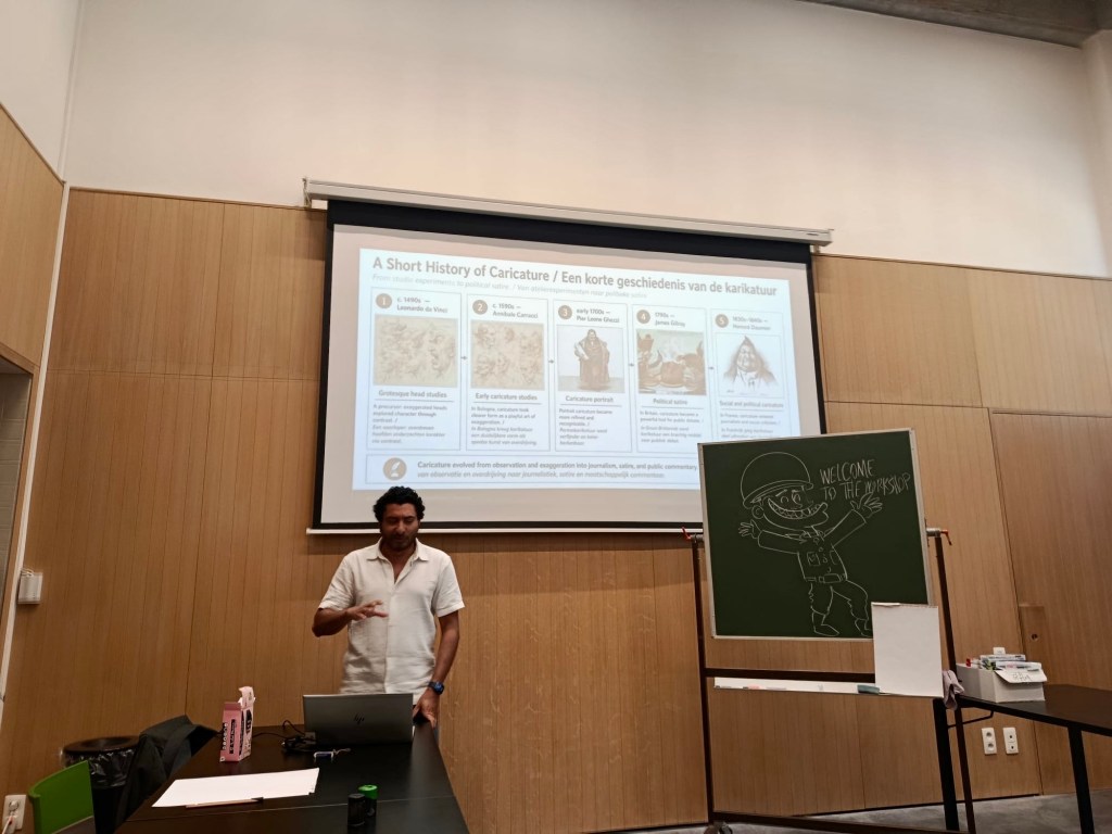 Sameh Samir conducting a political caricature workshop at the Ypres World War I Museum, using a chalkboard and projector.
