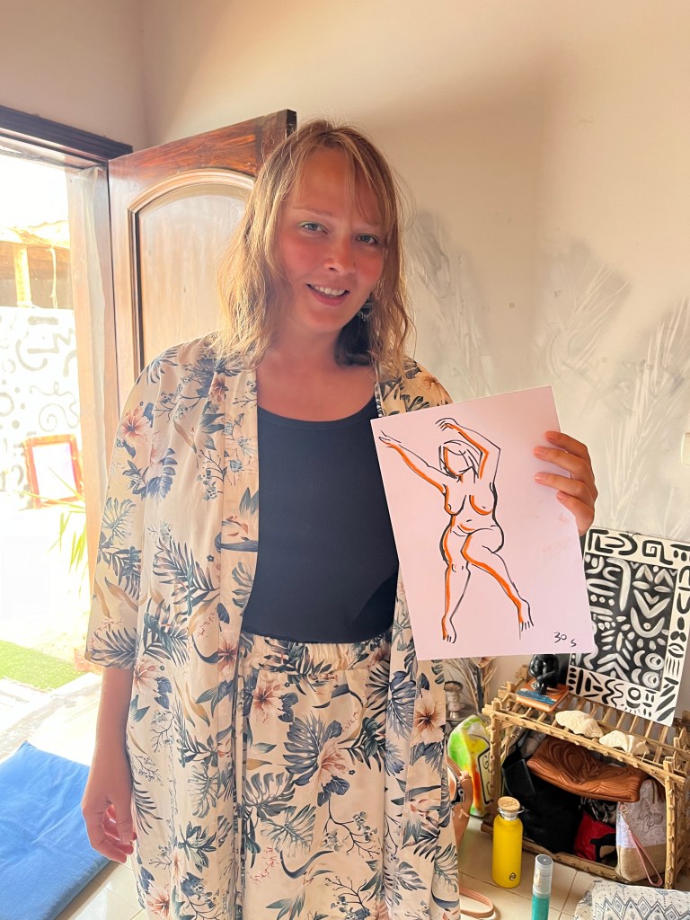 A life model holds a drawing of herself created by Sameh Samir during a nude art session.