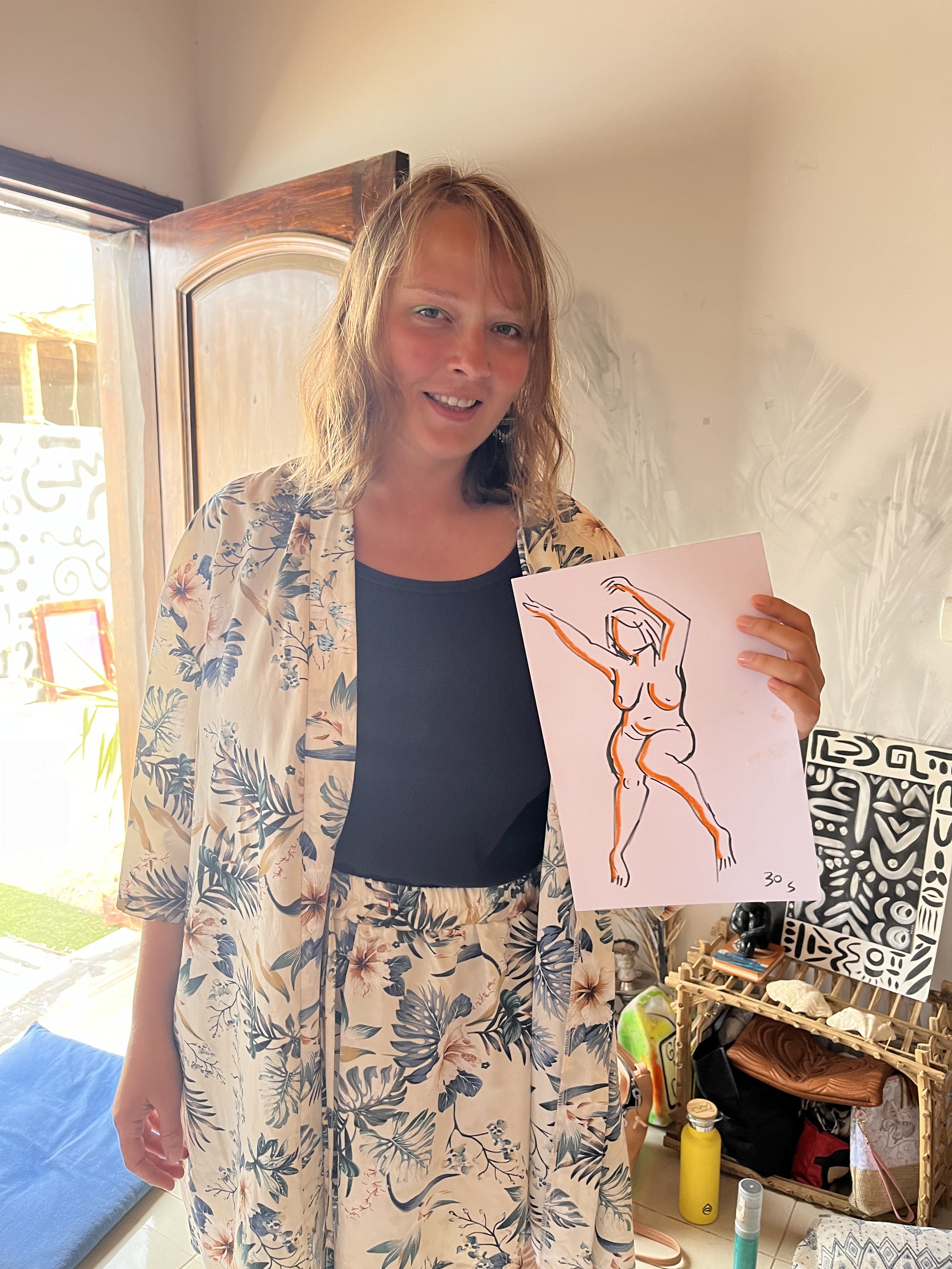 A life model holding a drawing made during a live art session.