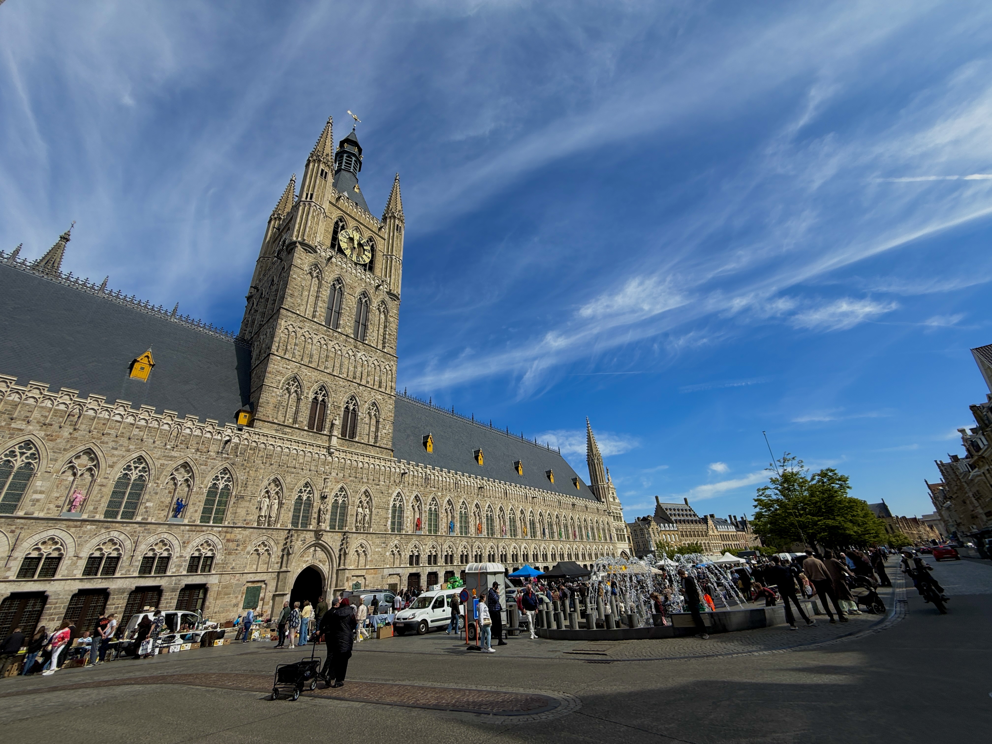 The iconic clock tower of Ieper, Belgium, standing tall against a clear blue sky.