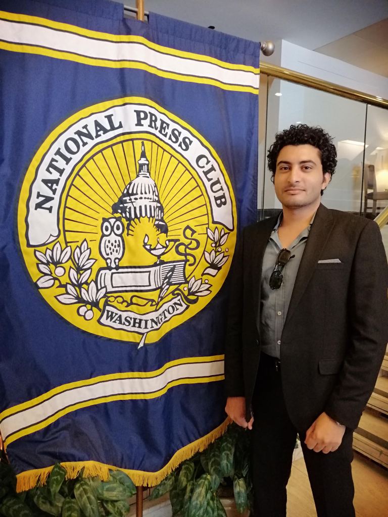 Person standing next to National Press Club banner in Washington.
