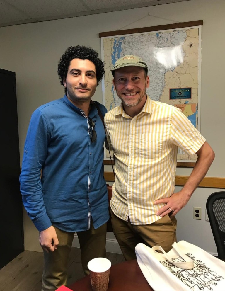 Sameh and a cartoonist friend posing in front of a map in a USA office