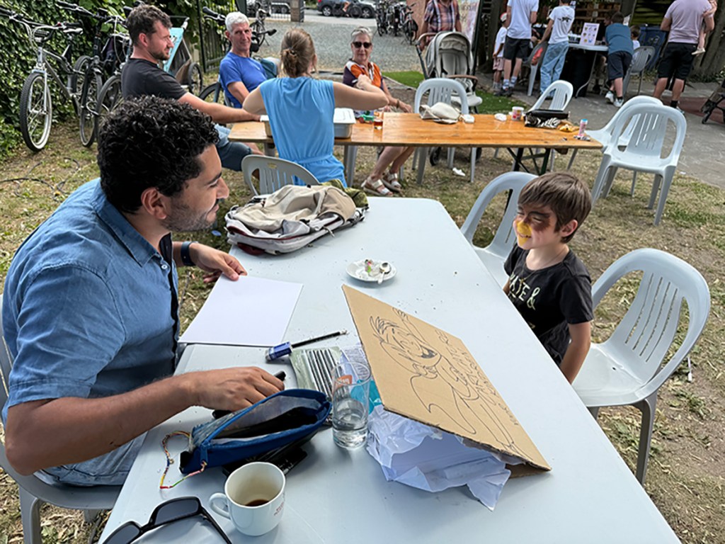 Sameh Cartoon artist drawing a live caricature for a child at a school event in Buggenhout, Belgium.