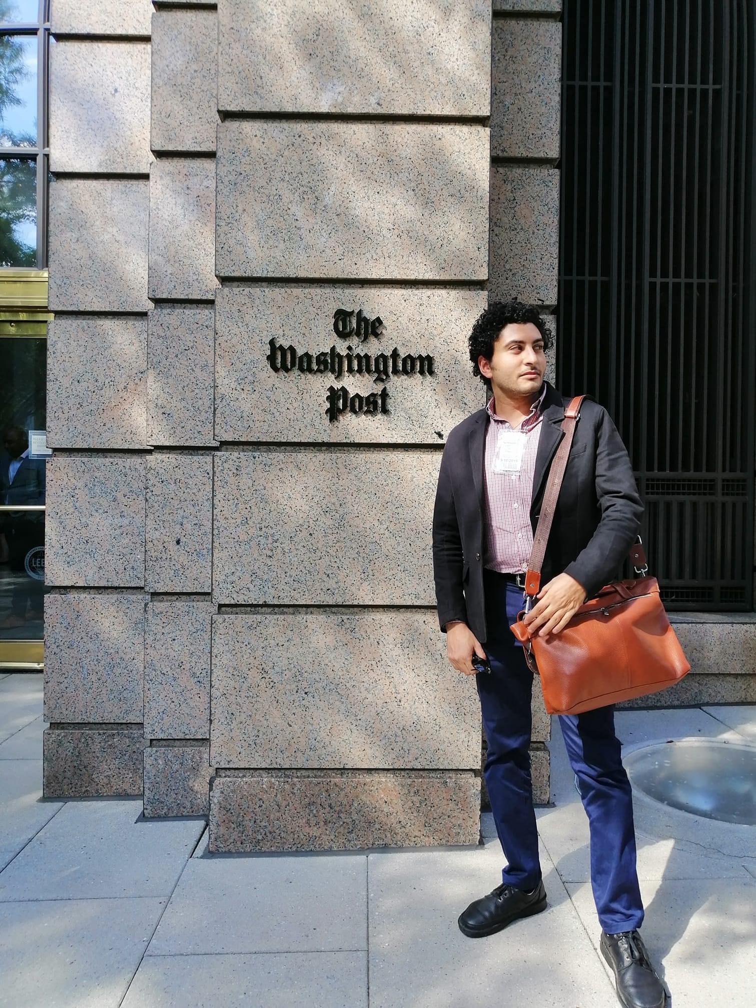 Person standing in front of The Washington Post building, corporate photo.