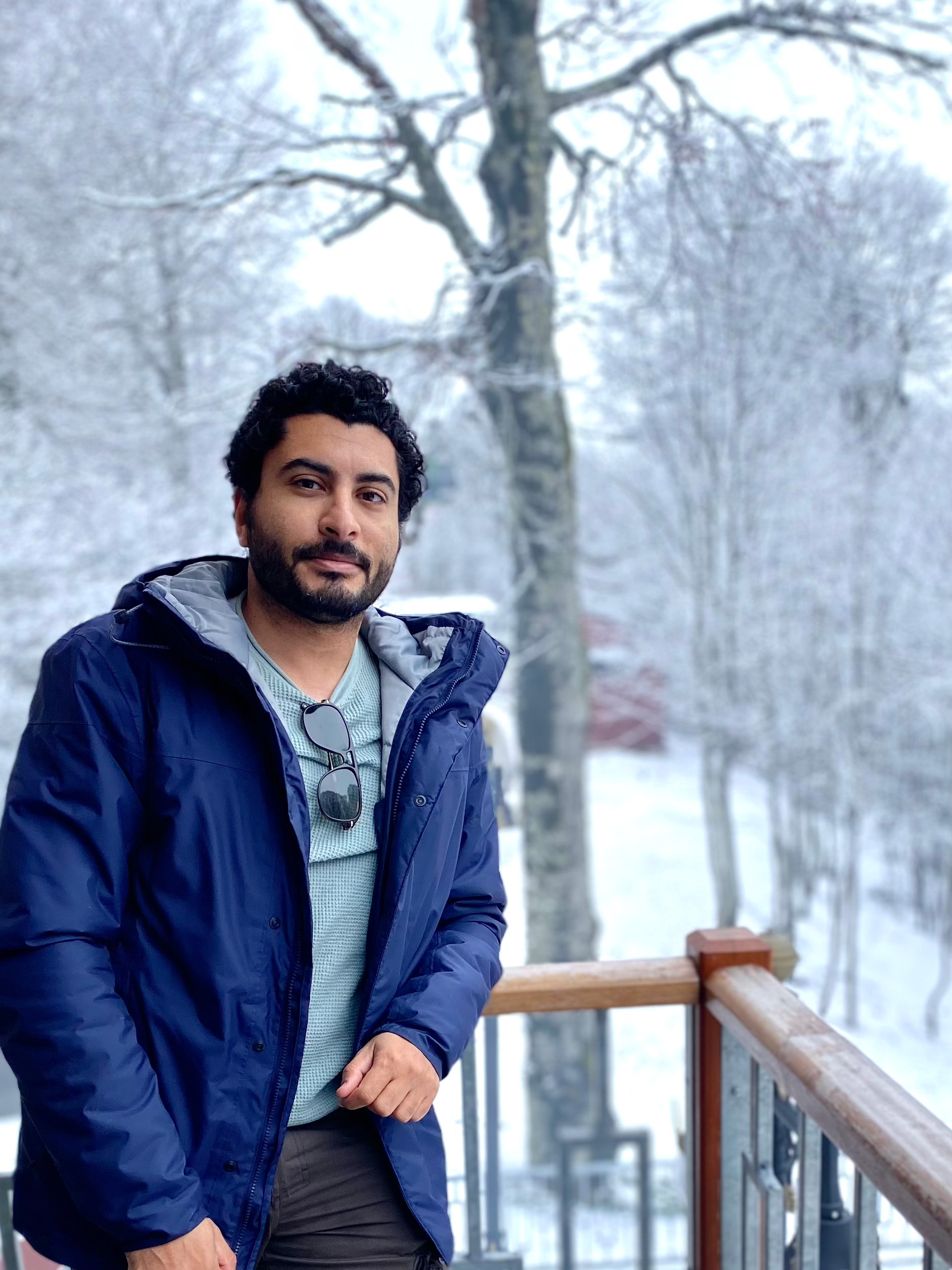 Sameh Samir standing on a snow-covered balcony in winter clothing