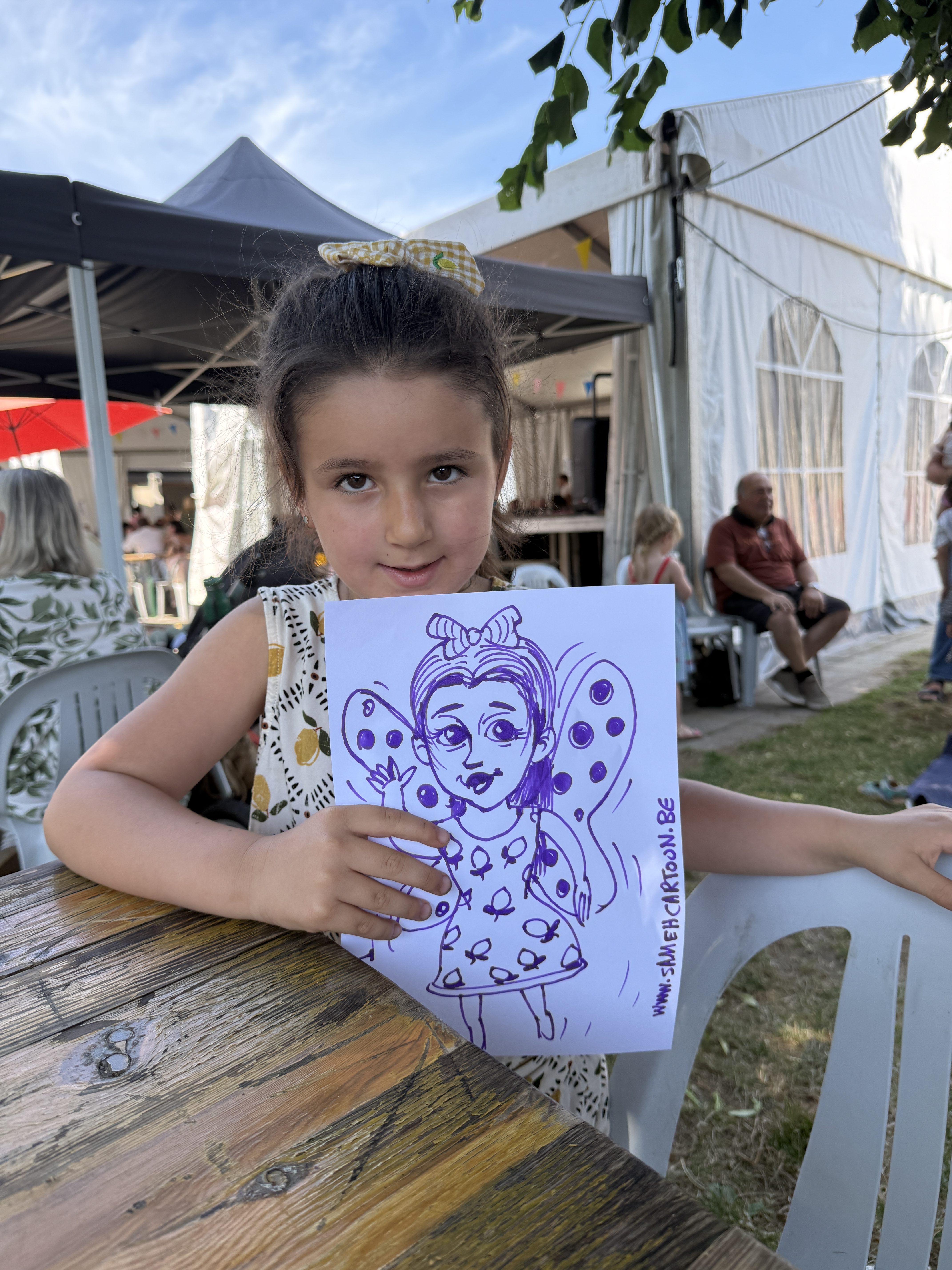 Child proudly showing her fairy caricature at a live event in Belgium
