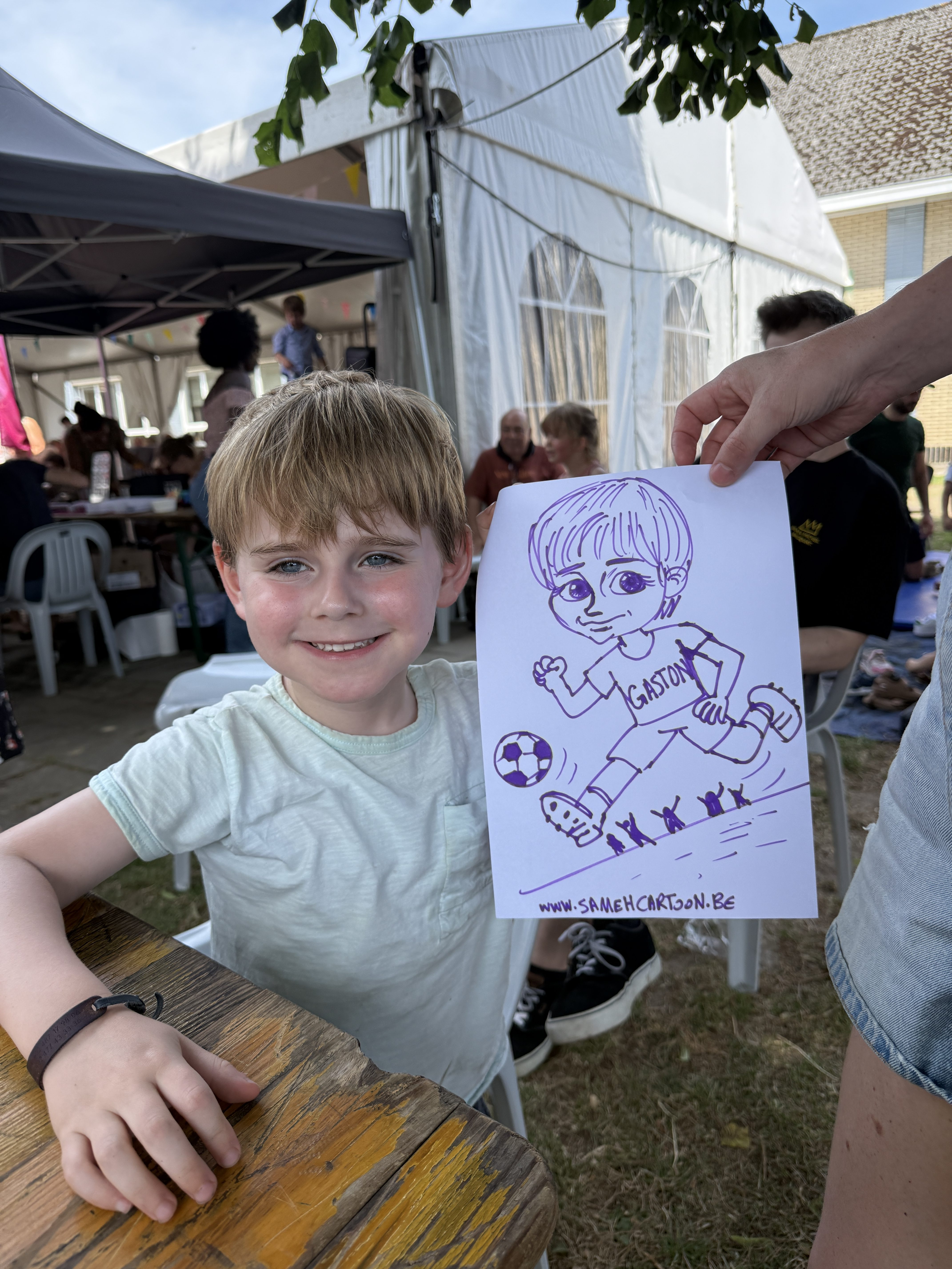 Child smiling with a football-themed caricature drawing