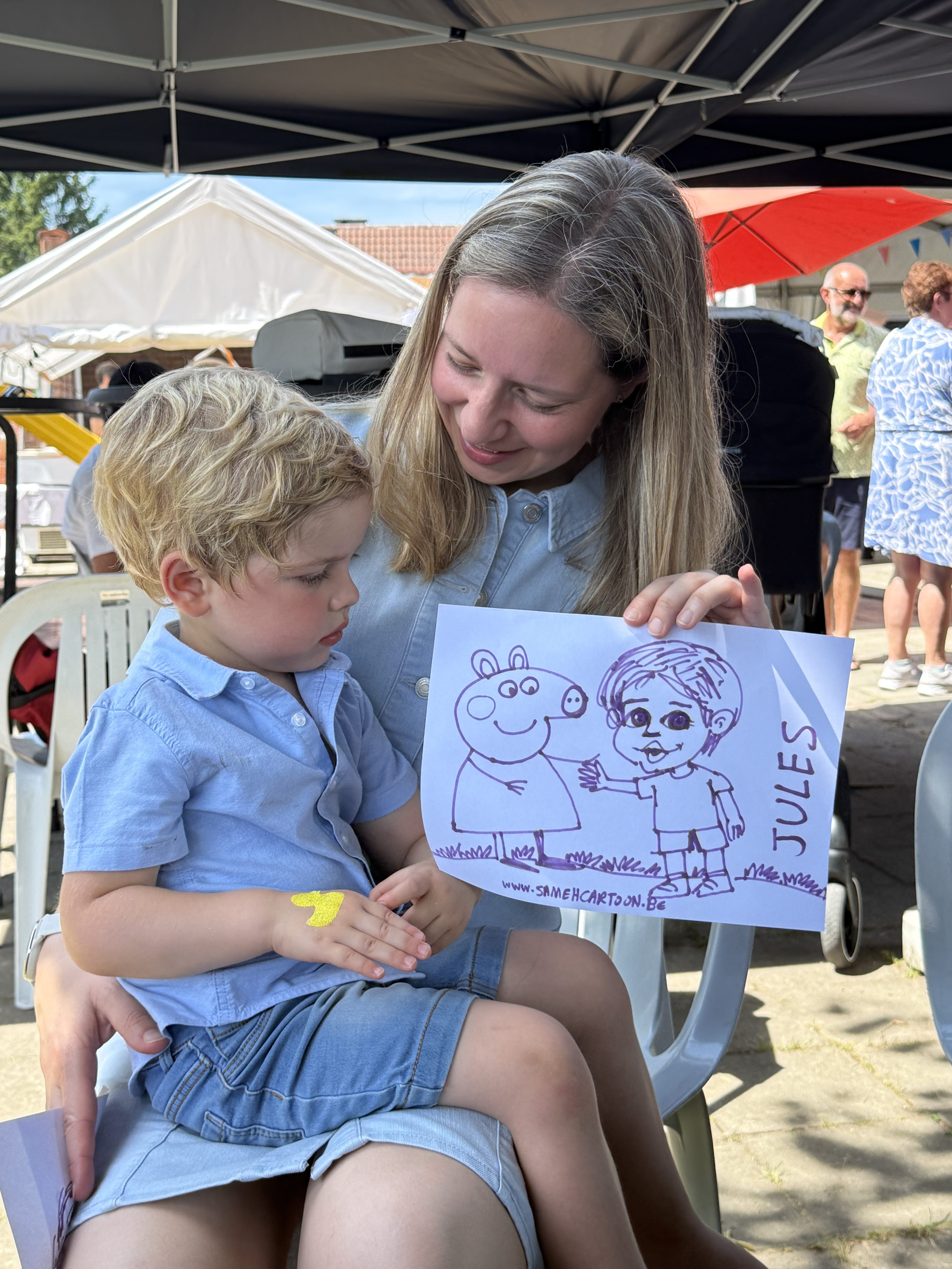Woman and child holding their cartoon drawing at a family event